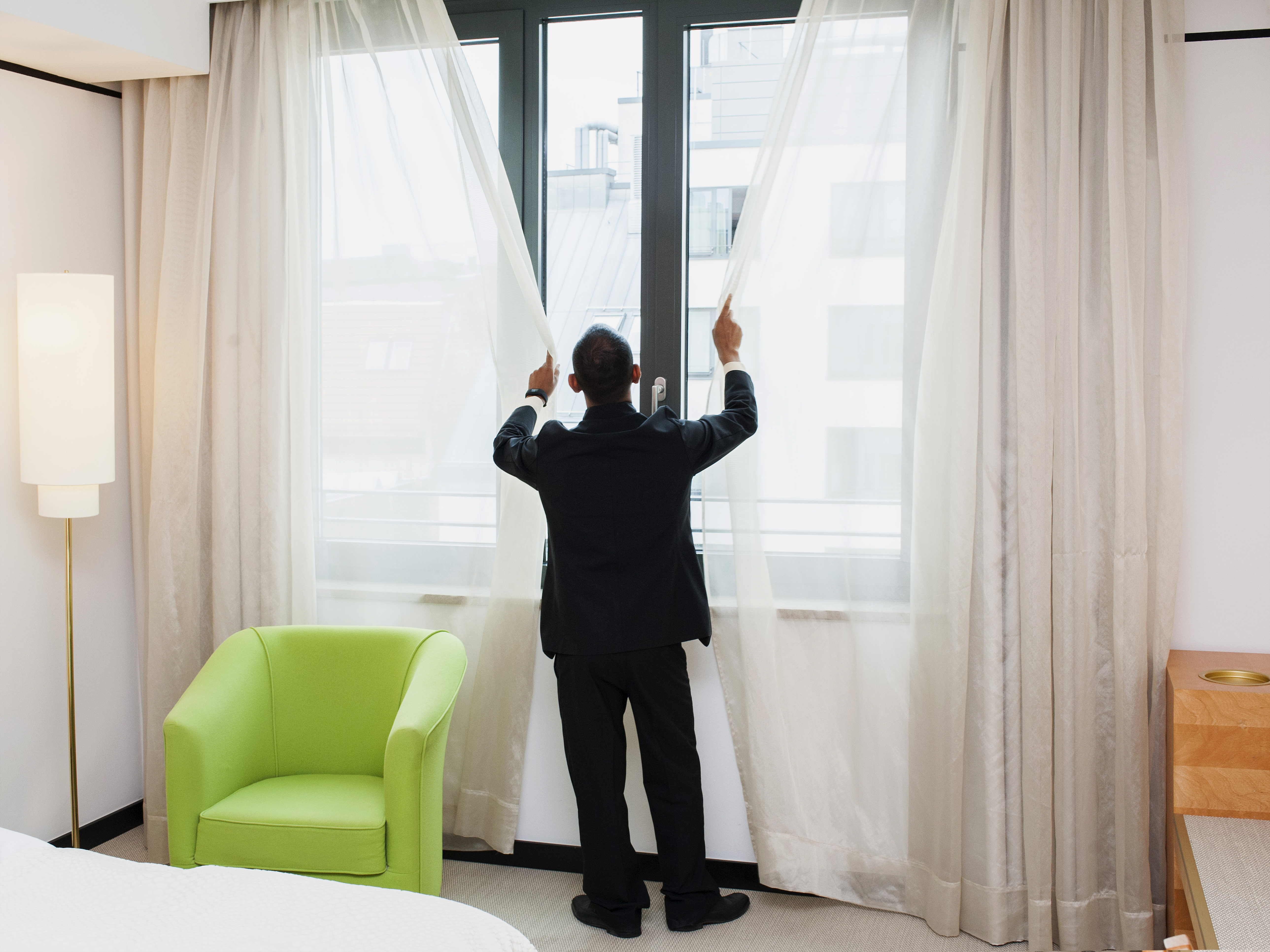 Hotelmitarbeiter zieht Vorhänge zu